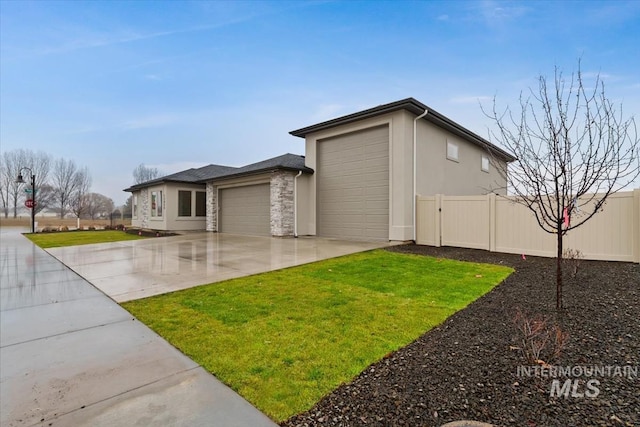 exterior space with a garage, fence, driveway, stucco siding, and a front yard