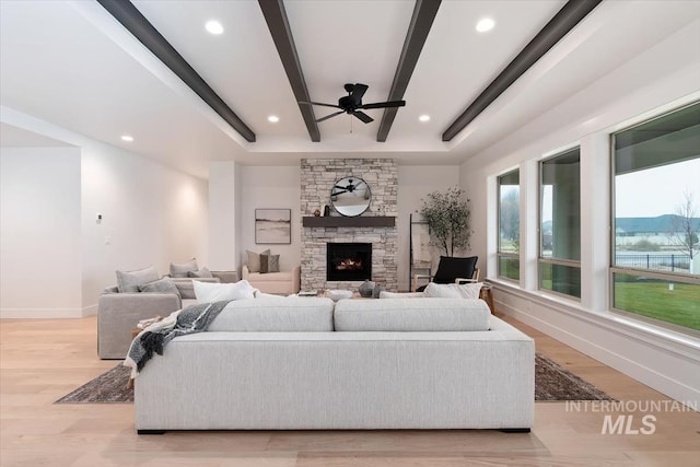 living area with recessed lighting, a fireplace, baseboards, light wood finished floors, and beamed ceiling