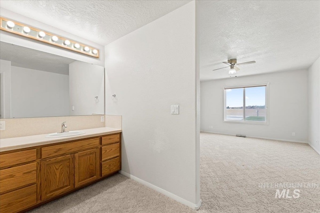 bathroom featuring baseboards, a textured ceiling, vanity, and ceiling fan