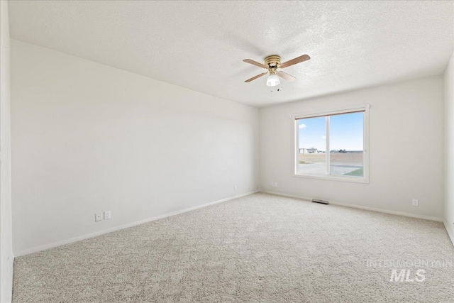 unfurnished room with a textured ceiling, carpet flooring, a ceiling fan, and baseboards