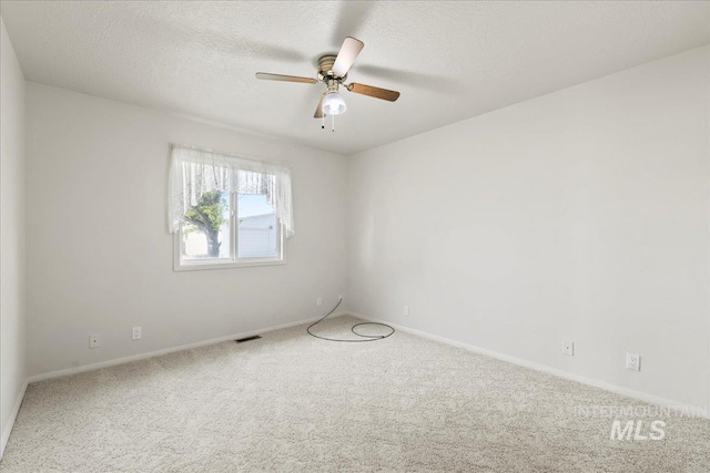 empty room with a ceiling fan, a textured ceiling, carpet, baseboards, and visible vents