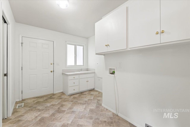 washroom with a sink, visible vents, washer hookup, stone finish floor, and cabinet space