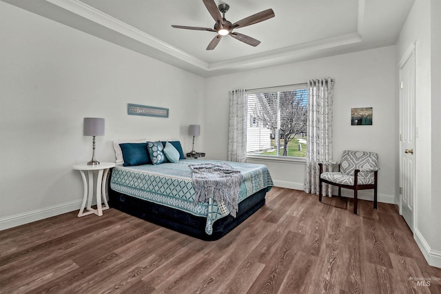 bedroom with a raised ceiling, wood finished floors, and baseboards