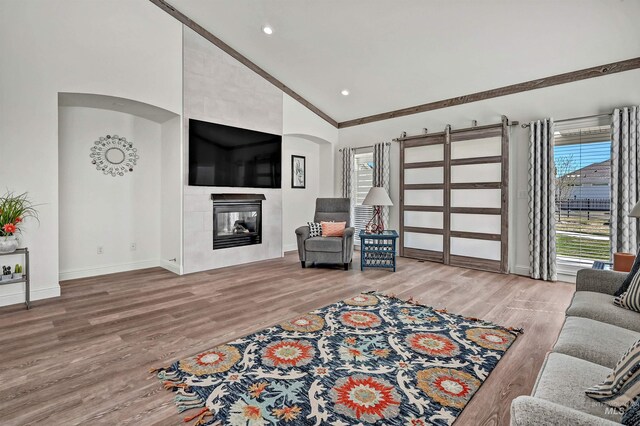 living room with recessed lighting, a tile fireplace, high vaulted ceiling, baseboards, and wood finished floors
