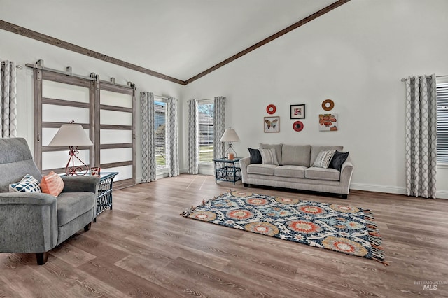 living area with wood finished floors, crown molding, high vaulted ceiling, and baseboards
