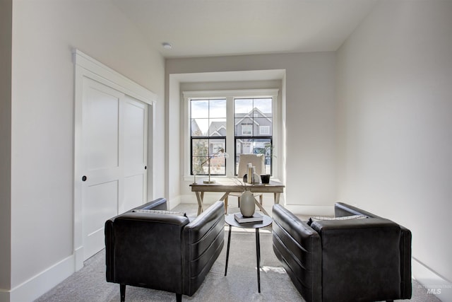 living area featuring carpet, a desk, and baseboards