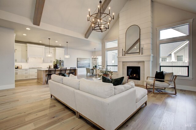 living room featuring a chandelier, recessed lighting, high vaulted ceiling, light wood-style flooring, and a fireplace