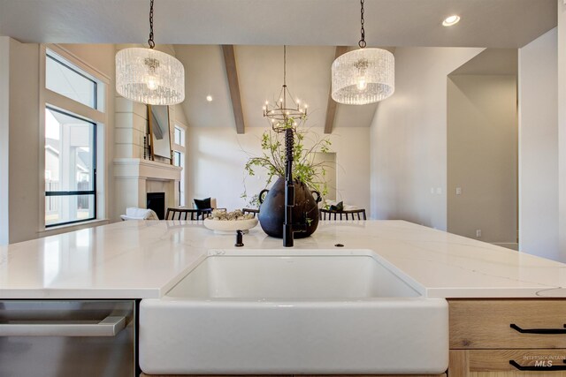 kitchen featuring dishwasher, a fireplace, a chandelier, light stone counters, and decorative light fixtures