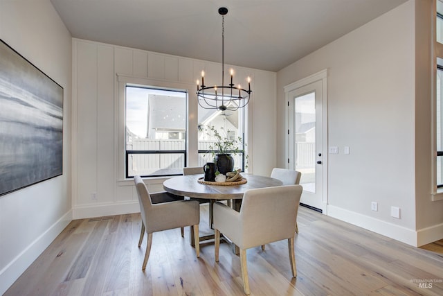 dining room with a chandelier, light wood finished floors, healthy amount of natural light, and baseboards