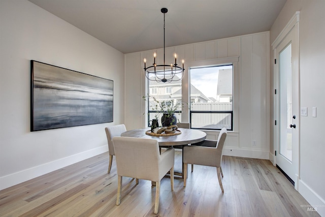dining room featuring light wood-type flooring, a chandelier, and baseboards