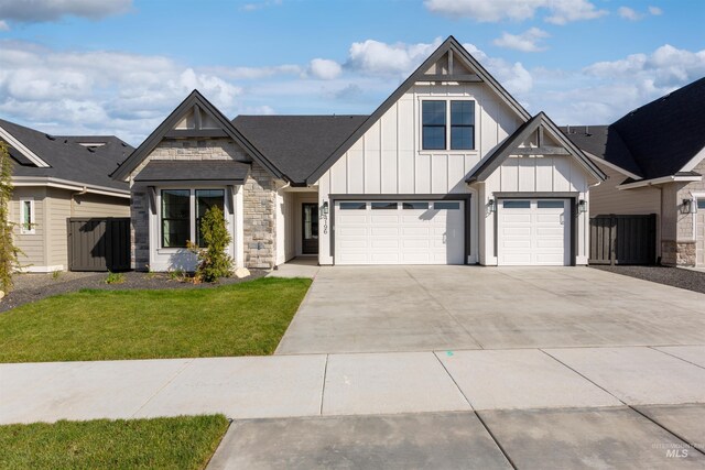 view of front of property with board and batten siding, driveway, a garage, and stone siding