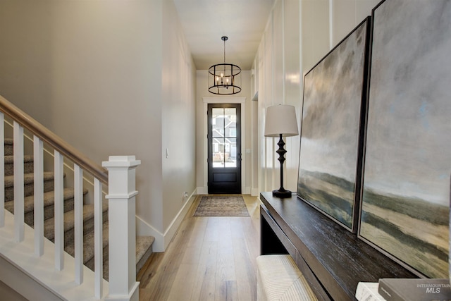 foyer with light wood-style floors, a chandelier, baseboards, and stairway