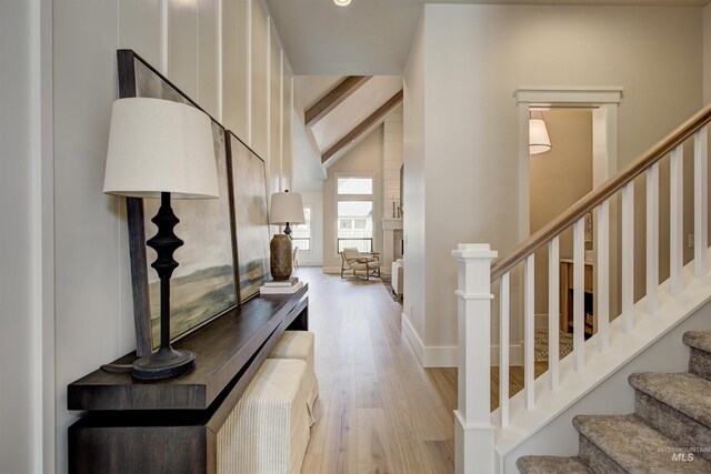 entryway with wood finished floors, stairway, beamed ceiling, and high vaulted ceiling
