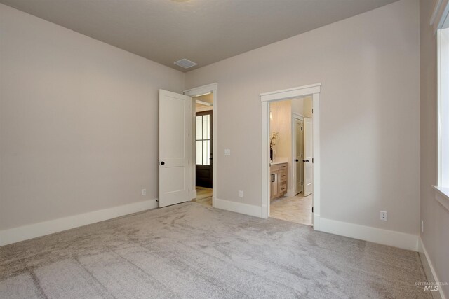 unfurnished bedroom featuring light colored carpet, baseboards, and connected bathroom