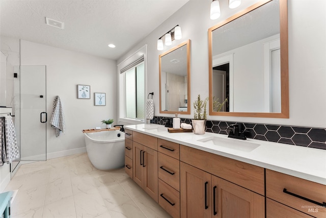 2255 N Sugar Loop Ave, Star, ID 83669 - bathroom with double vanity, marble look tile flooring, a shower stall, a freestanding tub, and decorative backsplash