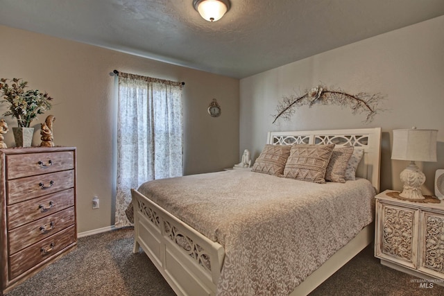 bedroom with dark colored carpet and a textured ceiling