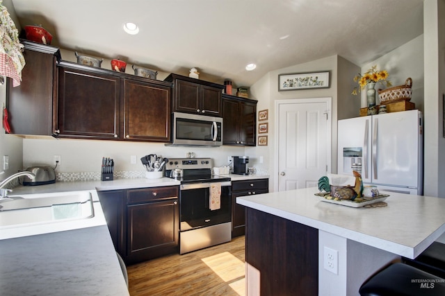 kitchen with stainless steel appliances, light countertops, a sink, and a kitchen island