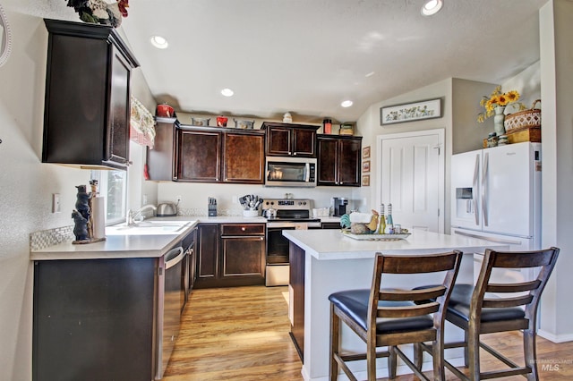 kitchen featuring stainless steel appliances, a center island, light countertops, and a kitchen breakfast bar