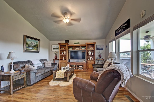 living room with a ceiling fan, lofted ceiling, baseboards, and wood finished floors