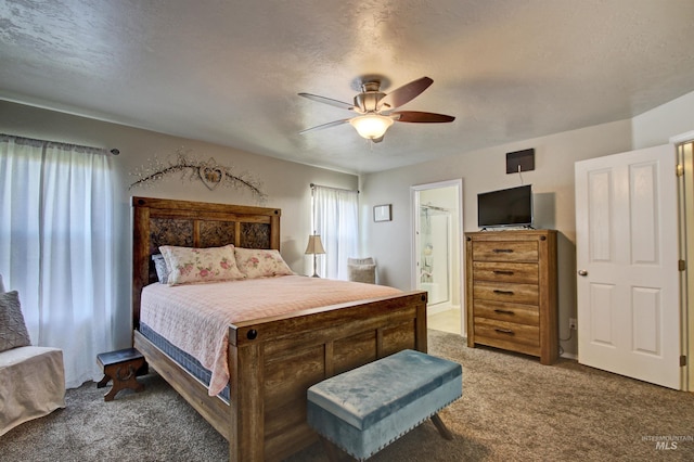 bedroom featuring a ceiling fan, dark colored carpet, a textured ceiling, and ensuite bathroom