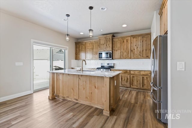 2065 Sombrero Ave, Middleton, ID 83644 - kitchen featuring stainless steel appliances, dark wood-type flooring, backsplash, a kitchen island with sink, and light stone countertops