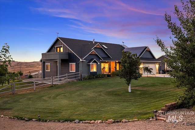 view of front of house with a yard, solar panels, a garage, and a balcony