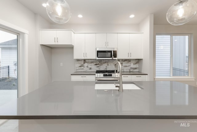 6760 S Cheyenne Ave, Boise, ID 83709 - kitchen featuring tasteful backsplash, light stone counters, stainless steel appliances, decorative light fixtures, and white cabinets
