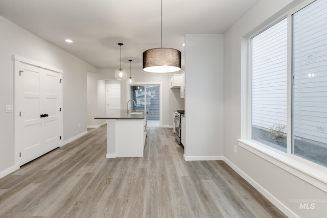 6760 S Cheyenne Ave, Boise, ID 83709 - kitchen featuring light wood-type flooring, dark countertops, a sink, and baseboards