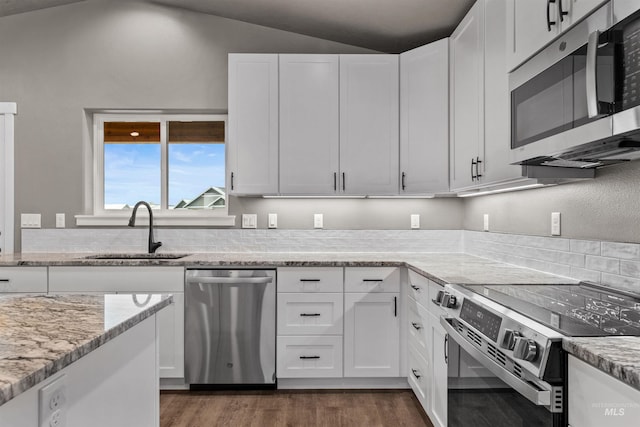 kitchen featuring light stone countertops, white cabinets, lofted ceiling, and appliances with stainless steel finishes