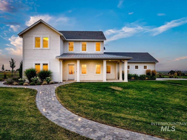 view of front of home with a standing seam roof, metal roof, and a yard