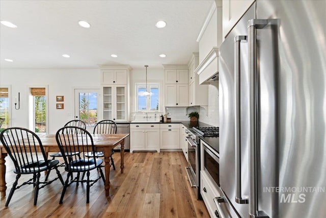 kitchen with premium appliances, plenty of natural light, dark countertops, and decorative backsplash