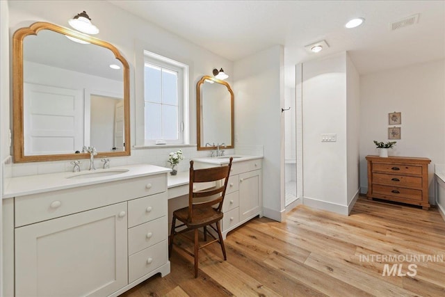 bathroom with tasteful backsplash, wood finished floors, visible vents, and a sink