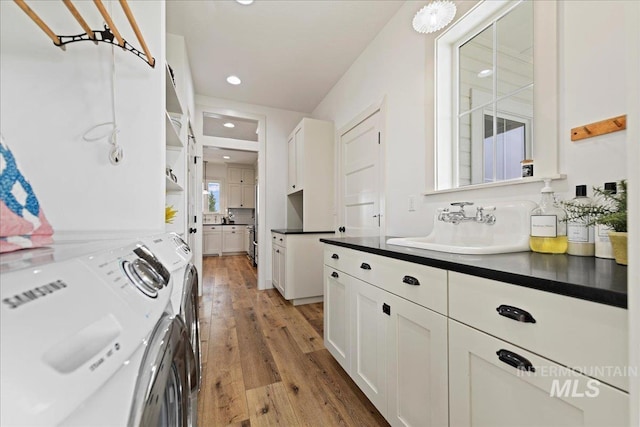 laundry room featuring light wood-type flooring, a sink, recessed lighting, cabinet space, and separate washer and dryer