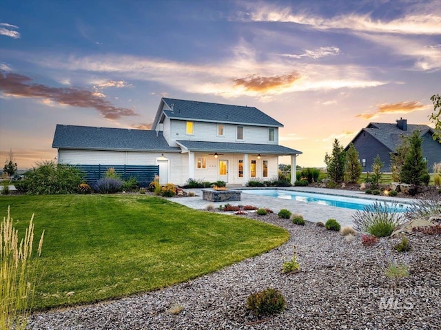 rear view of property with a patio, a yard, and a pool with connected hot tub