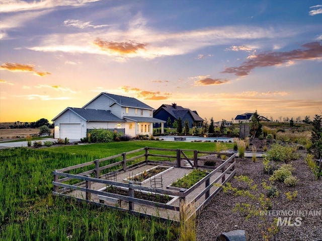 exterior space with fence, driveway, a vegetable garden, an attached garage, and a lawn