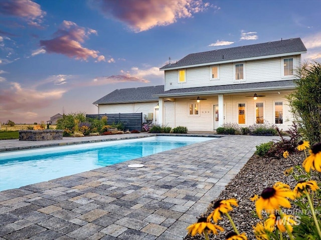 pool at dusk featuring a patio and an outdoor pool