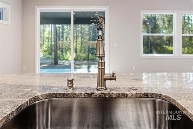 interior details featuring light stone counters and sink