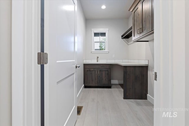 laundry area with light hardwood / wood-style floors and sink