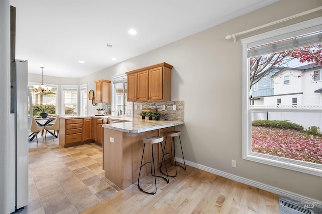 380 S Golden Eagle Ln, Eagle, ID 83616 - kitchen featuring a peninsula, a chandelier, freestanding refrigerator, backsplash, and a breakfast bar area