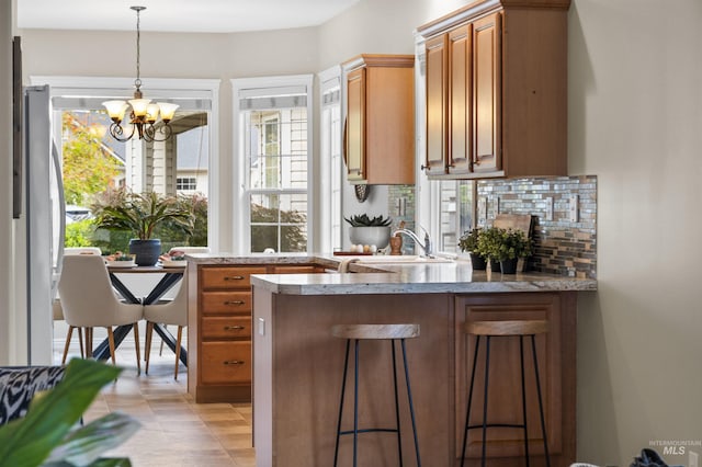 380 S Golden Eagle Ln, Eagle, ID 83616 - kitchen featuring a peninsula, a chandelier, healthy amount of natural light, and backsplash