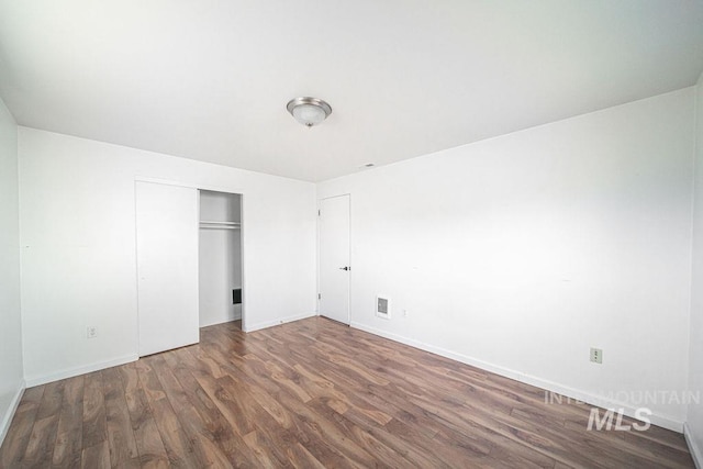 unfurnished bedroom with dark hardwood / wood-style flooring and a closet