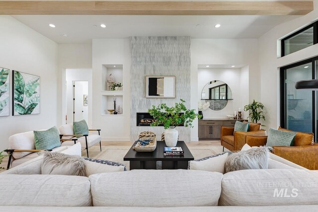 living room with built in shelves, a fireplace, and light hardwood / wood-style floors