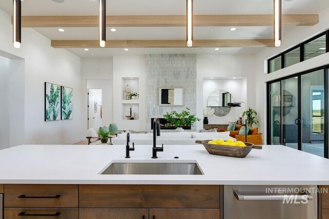 kitchen featuring a center island with sink, dishwasher, beam ceiling, and sink