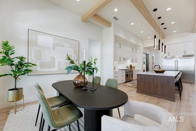 dining space featuring beam ceiling and light hardwood / wood-style flooring