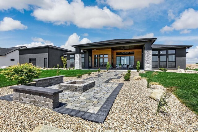 rear view of property featuring a yard, a fire pit, and a patio area