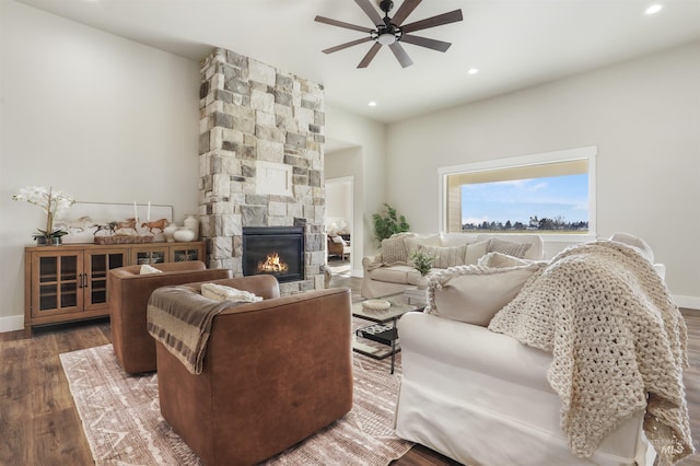 living room with dark hardwood / wood-style floors, a stone fireplace, and ceiling fan