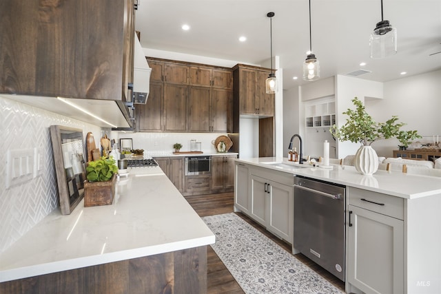 kitchen with a large island with sink, stainless steel dishwasher, pendant lighting, and sink