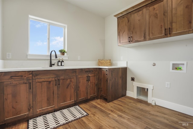 laundry room featuring cabinets, gas dryer hookup, electric dryer hookup, sink, and light hardwood / wood-style floors