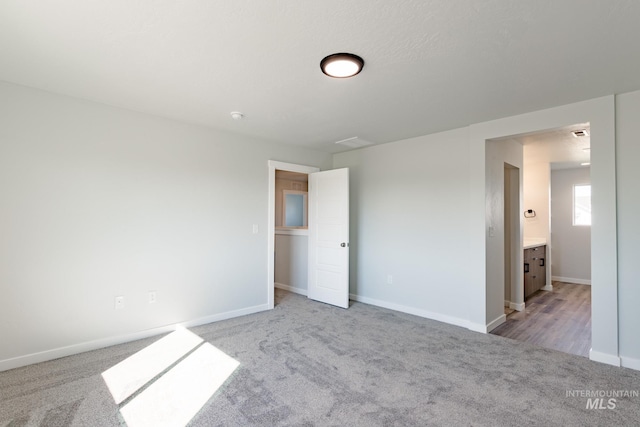 empty room featuring baseboards and light carpet