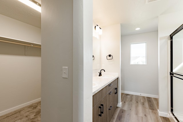 full bathroom featuring a walk in closet, double vanity, baseboards, and a sink